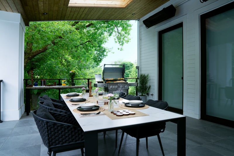 Rogue PRO 525 stainless steel grill open on a modern patio, grilling steaks and veggies with infrared side burner in use, outdoor dining setup in background in North Florida